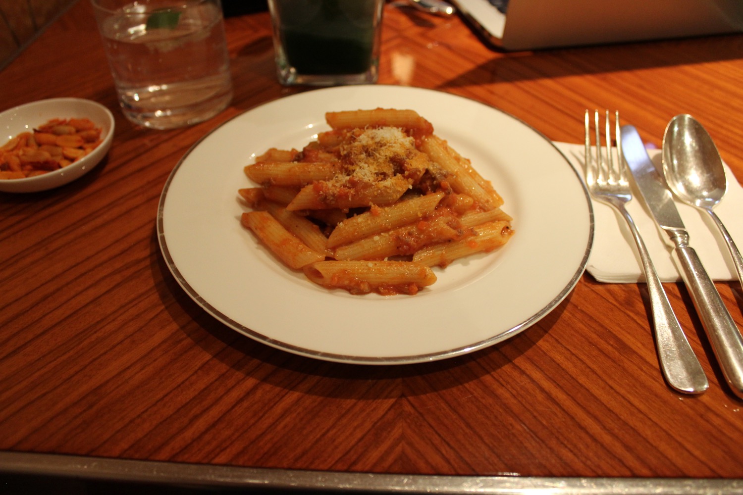 a plate of pasta with sauce and cheese on a wooden table