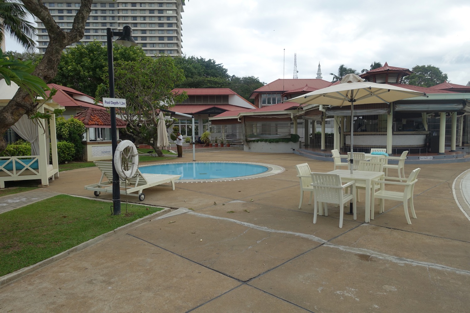 a pool with chairs and umbrellas in front of buildings