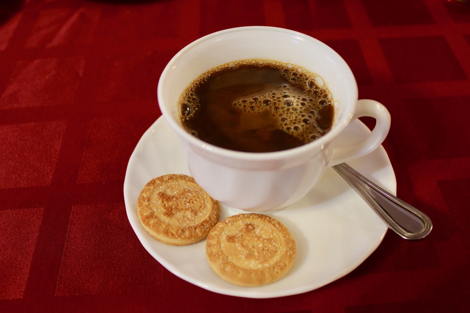 a cup of coffee and cookies on a plate