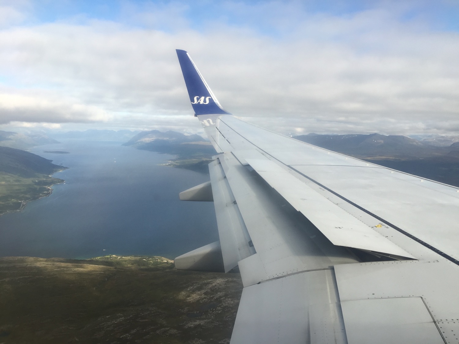 an airplane wing with land and water in the background
