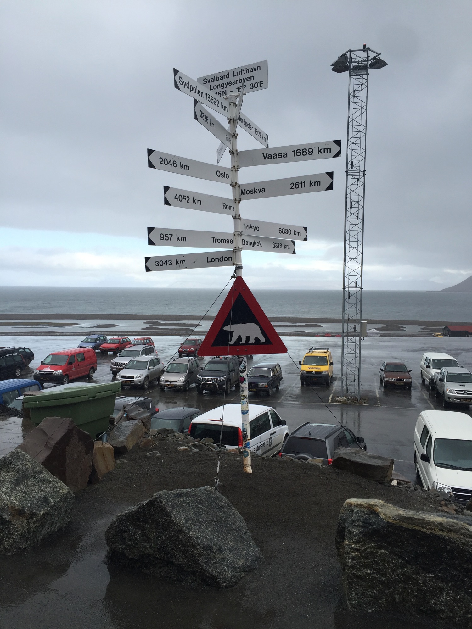 a signpost with a sign and a group of cars parked on a beach