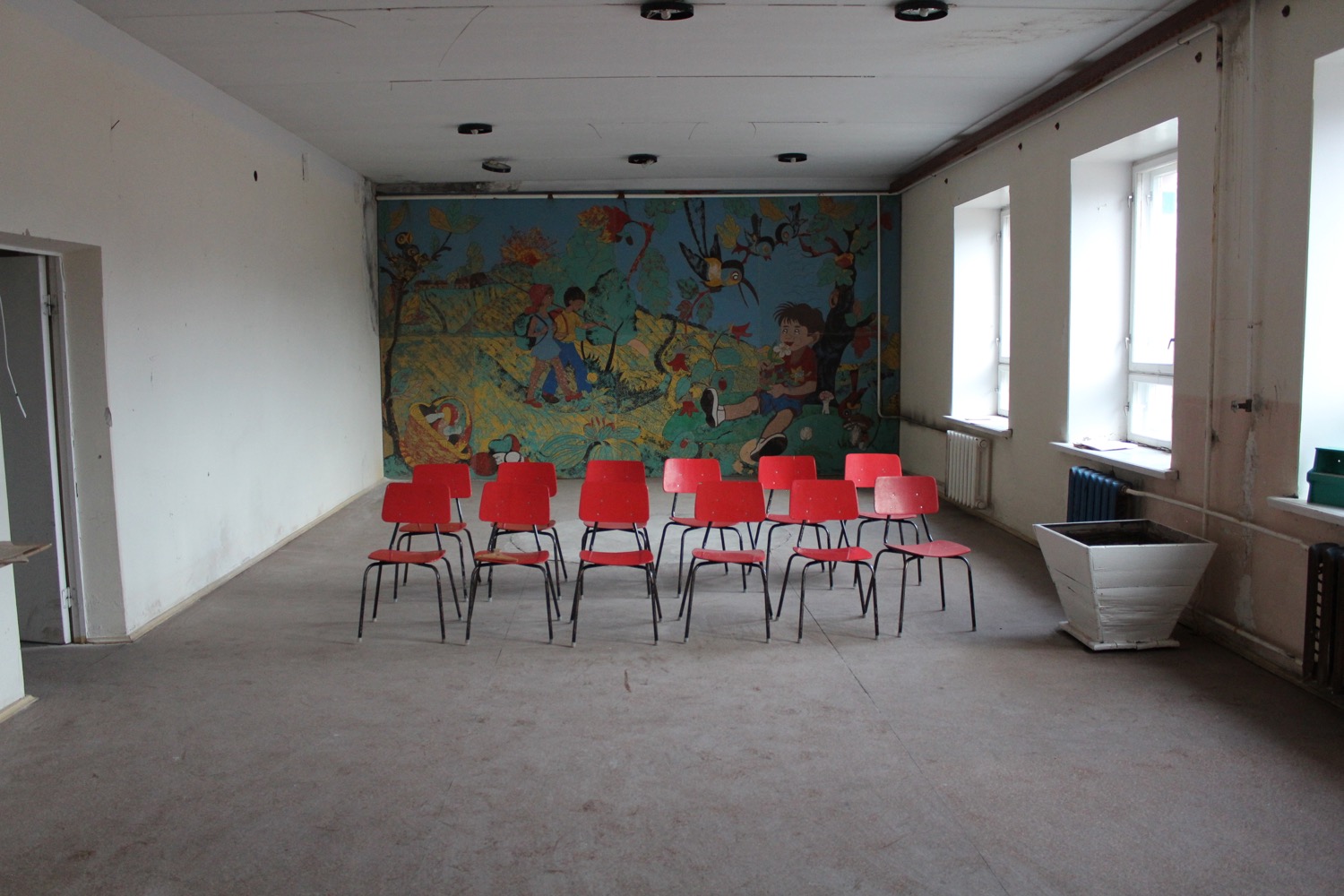 a room with red chairs and a mural on the wall