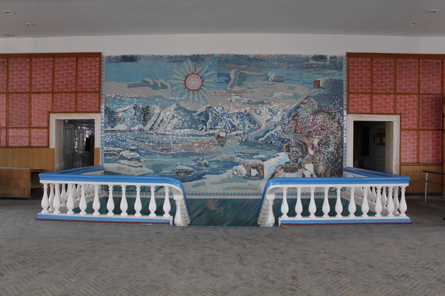 a mosaic wall with a white railing and blue railings