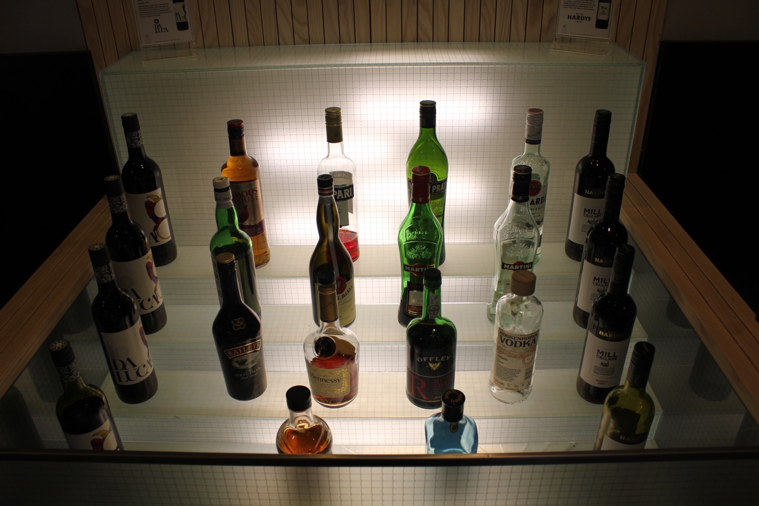 a group of bottles of alcohol on a glass shelf