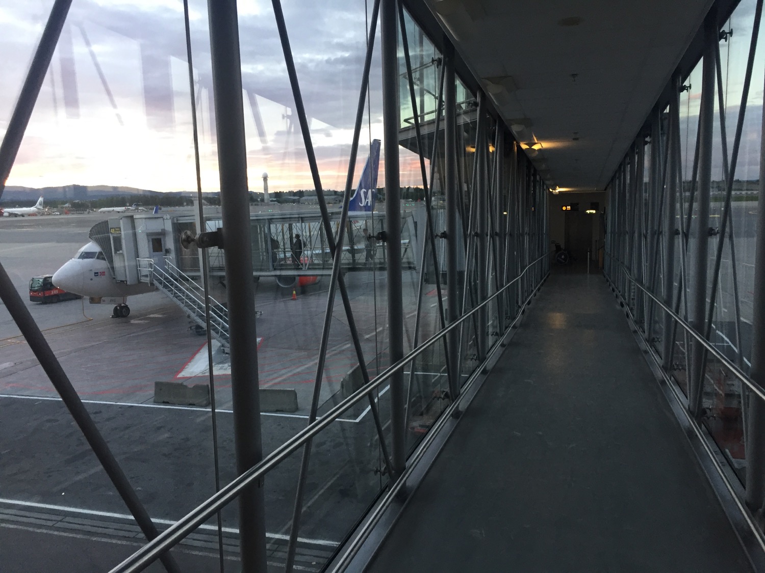 a walkway with glass walls and a plane in the background