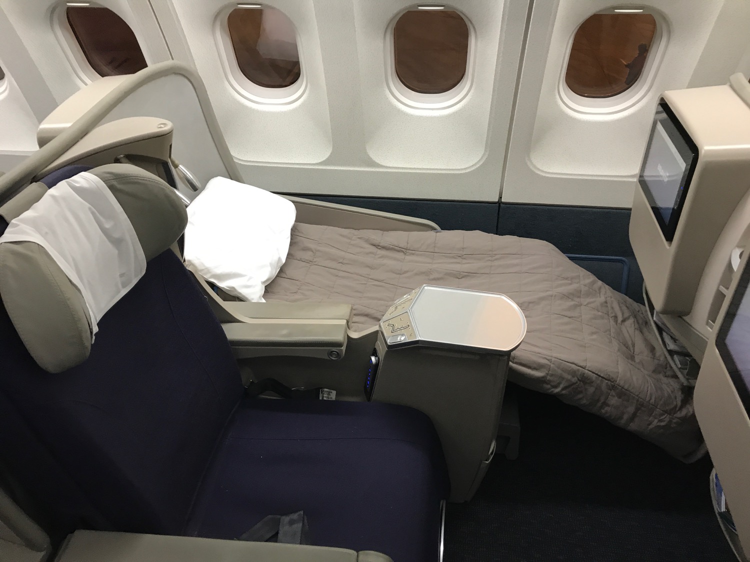 an airplane seat with a bed and a pillow
