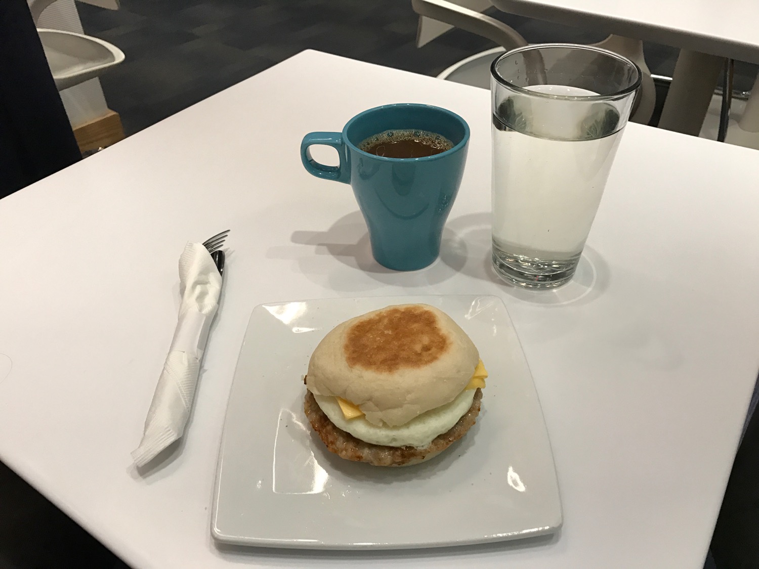a breakfast sandwich and a cup of coffee on a white table