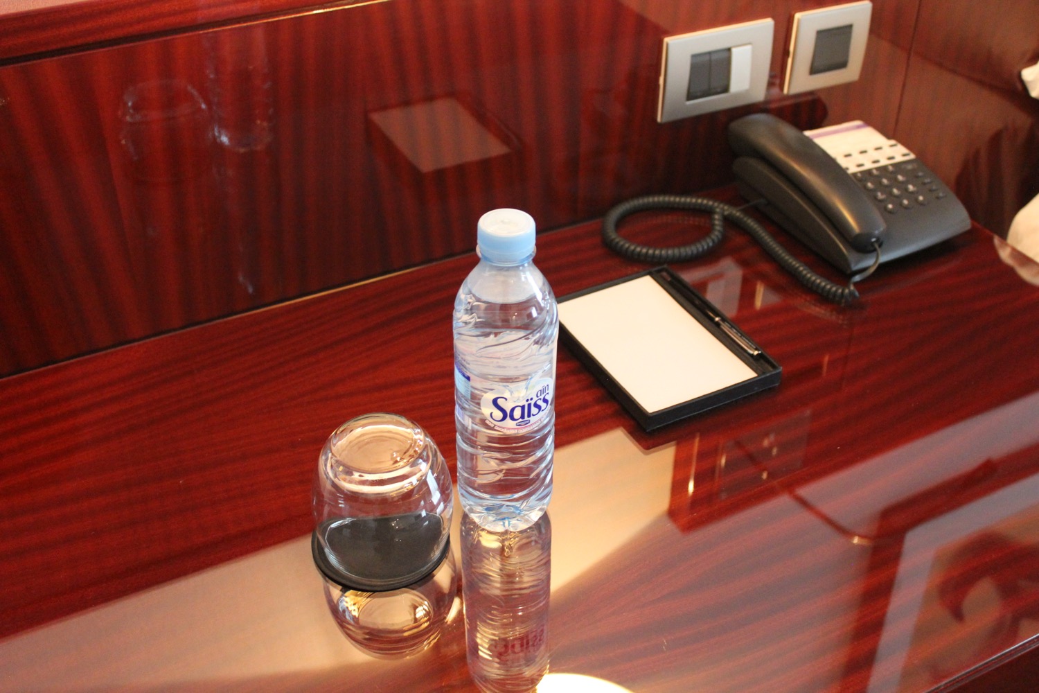 a bottle of water and a glass on a desk