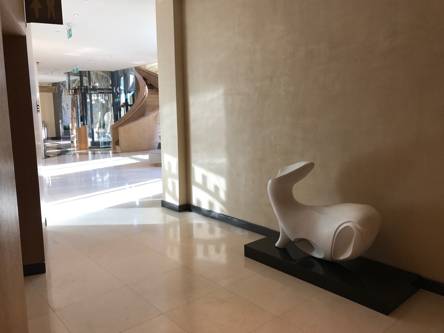 a white sculpture on a black stand in a hallway