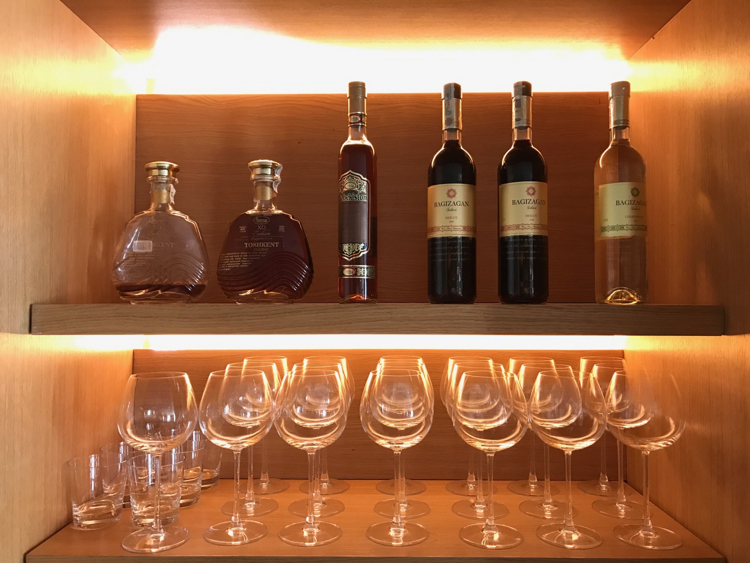 a shelf with wine bottles and glasses