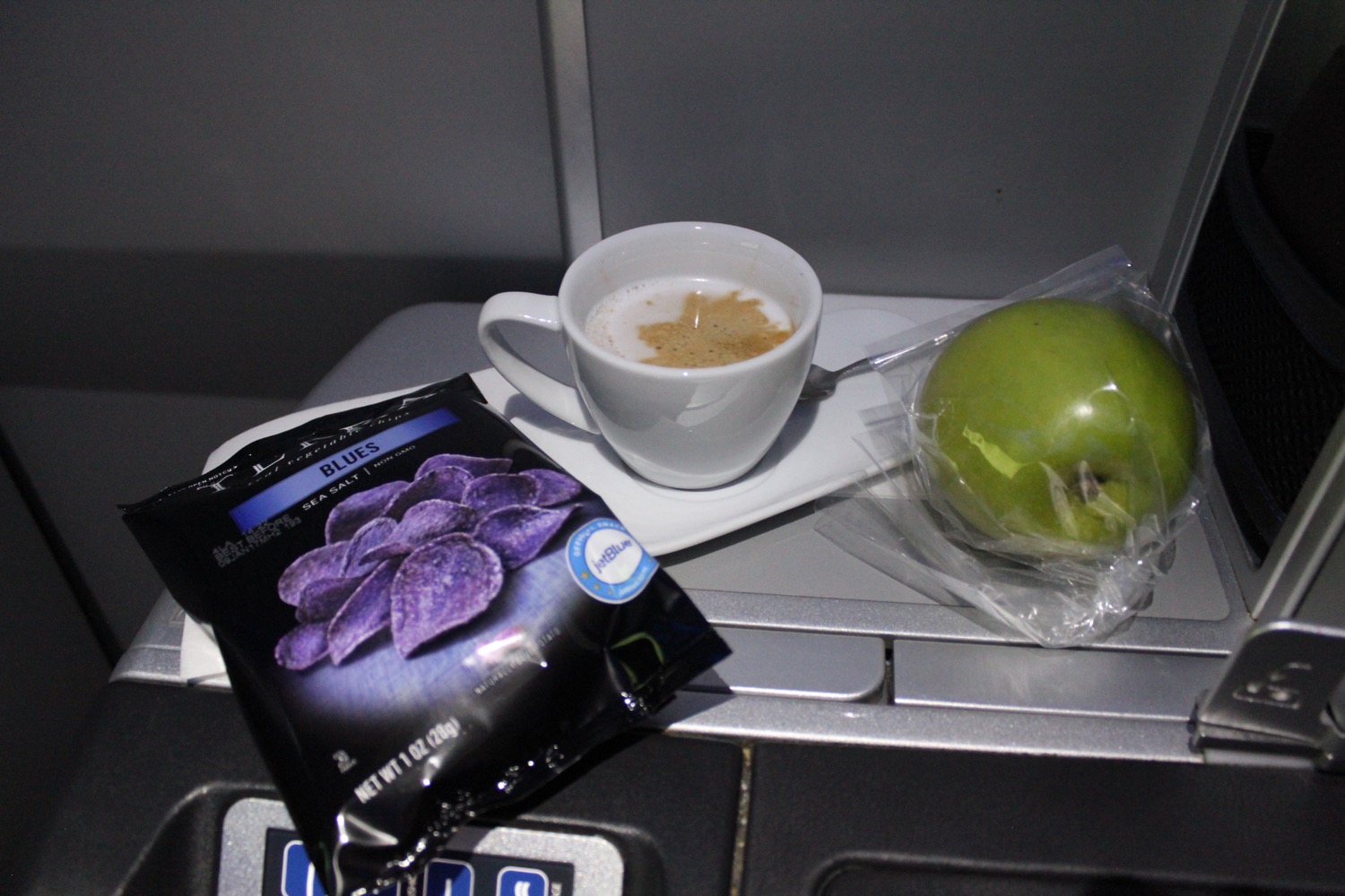 a cup of coffee and an apple on a tray