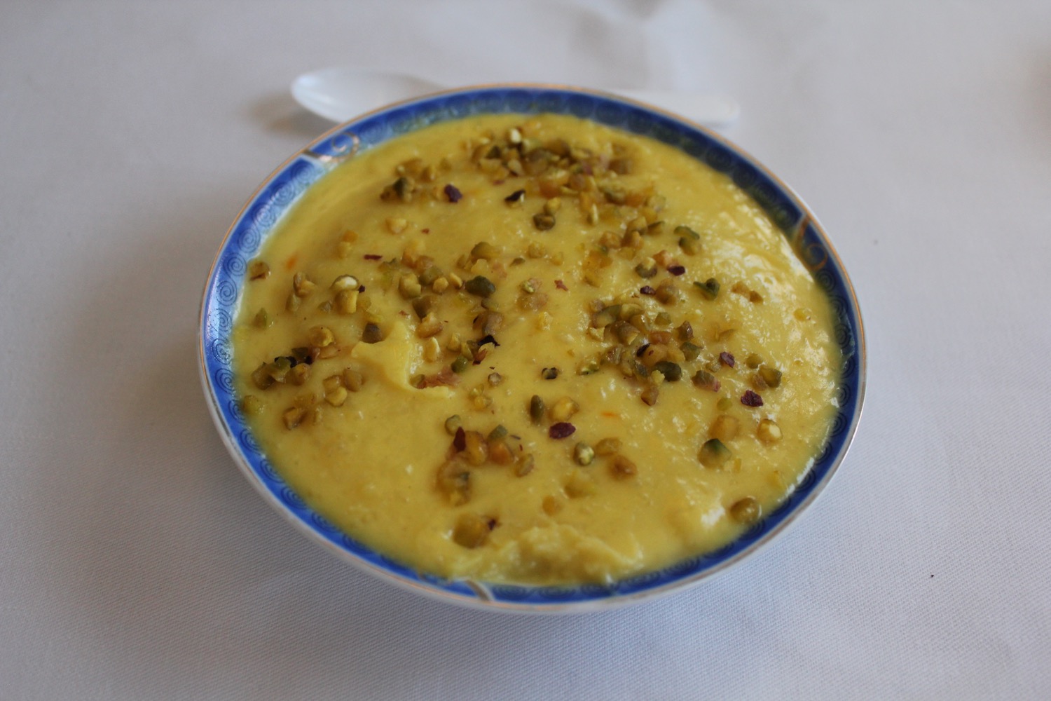 a bowl of yellow soup with green sprinkles