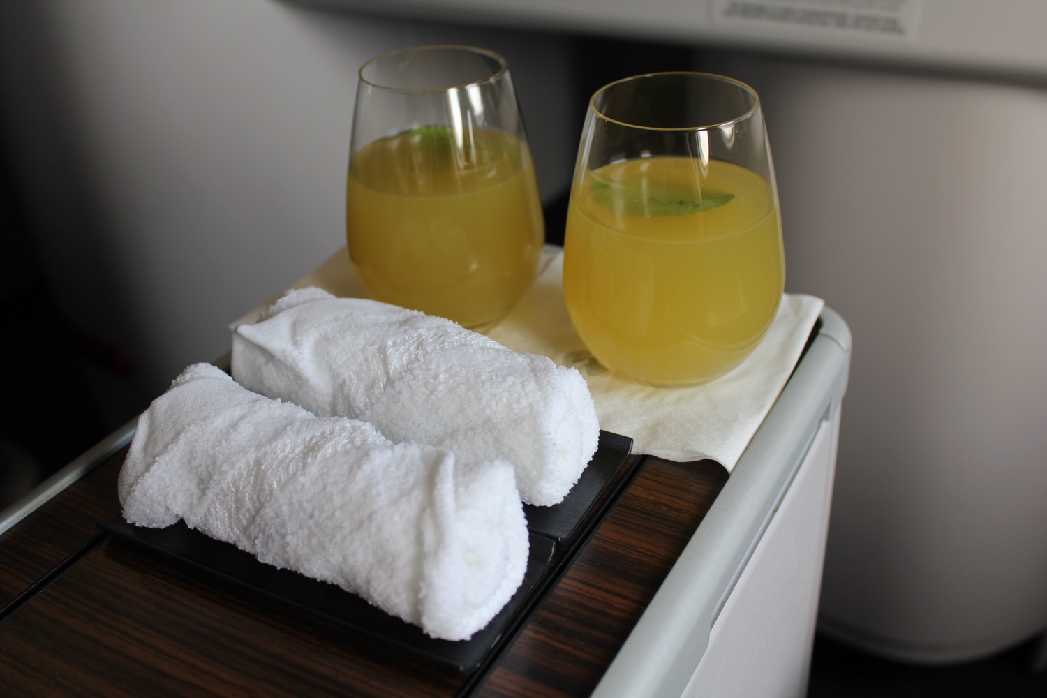 two glasses of orange liquid and towels on a tray
