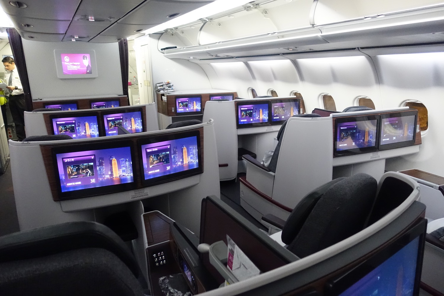 a row of seats with monitors on the side of the plane