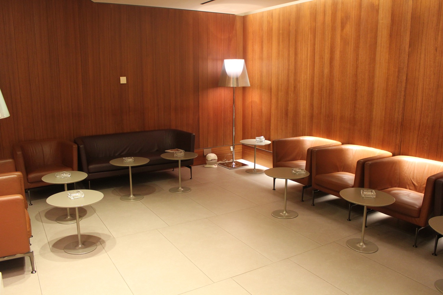 a room with a wood paneled wall and chairs and a lamp