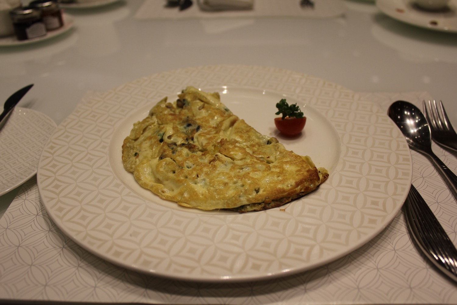 a plate of omelette with a small tomato on it