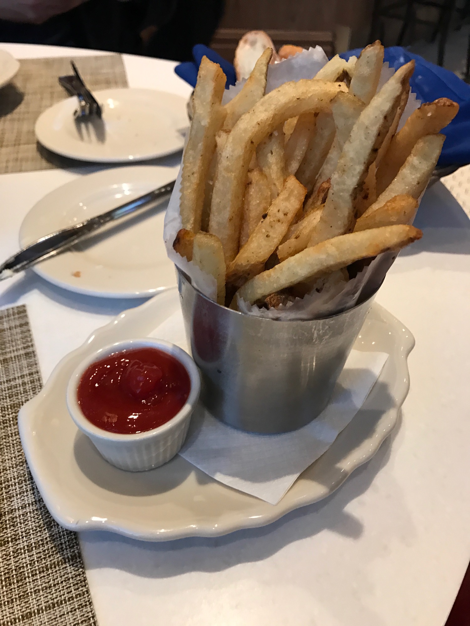 a bucket of french fries with ketchup on a plate