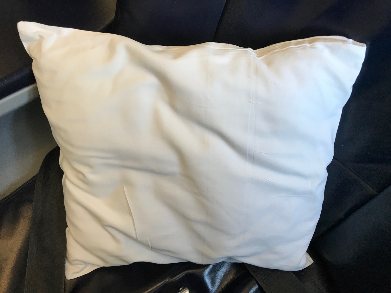 a white pillow on a black chair