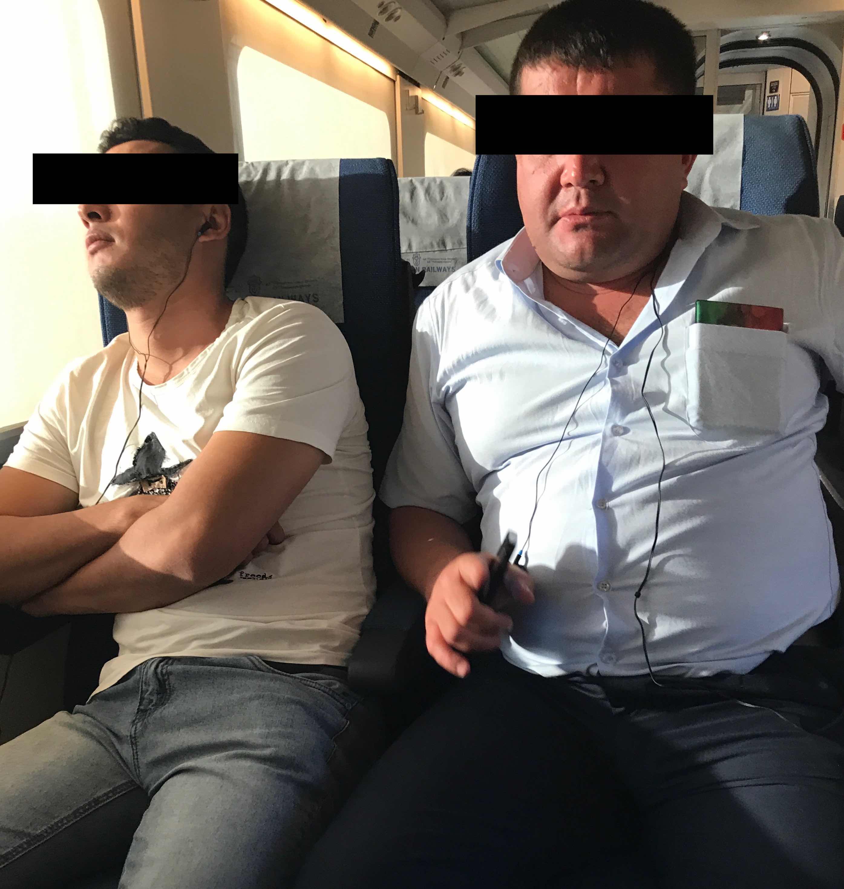 two men sitting on a train