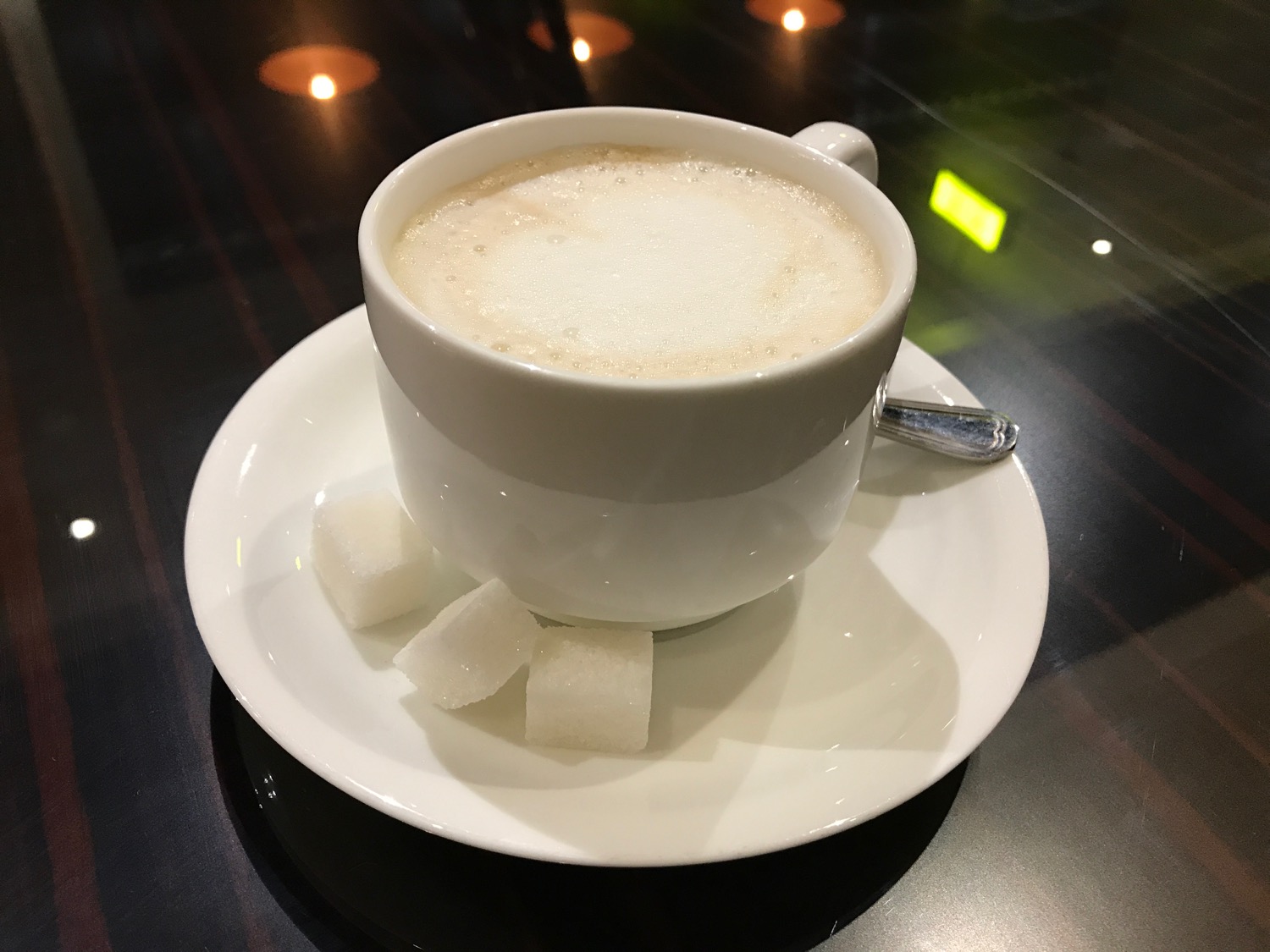 a cup of coffee with sugar cubes on a plate