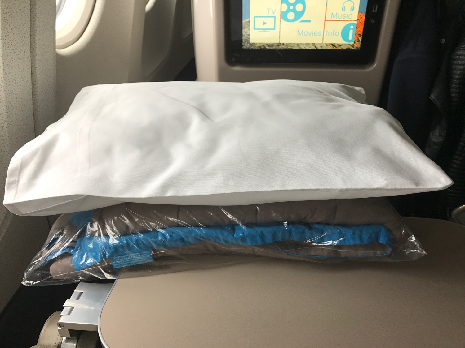 a white pillow and blue blanket in a plastic bag on a table