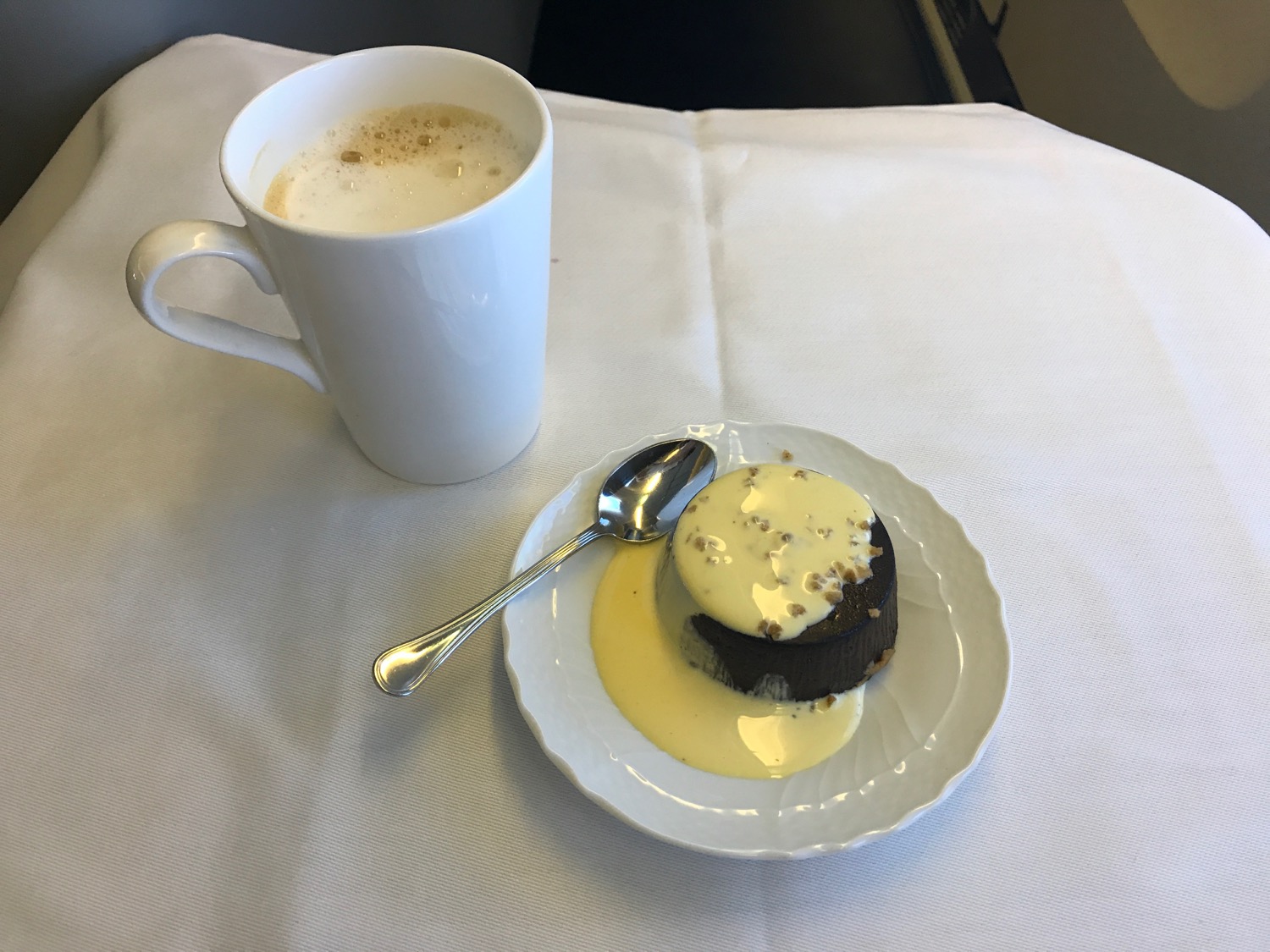 a plate of dessert with a spoon and a cup of coffee