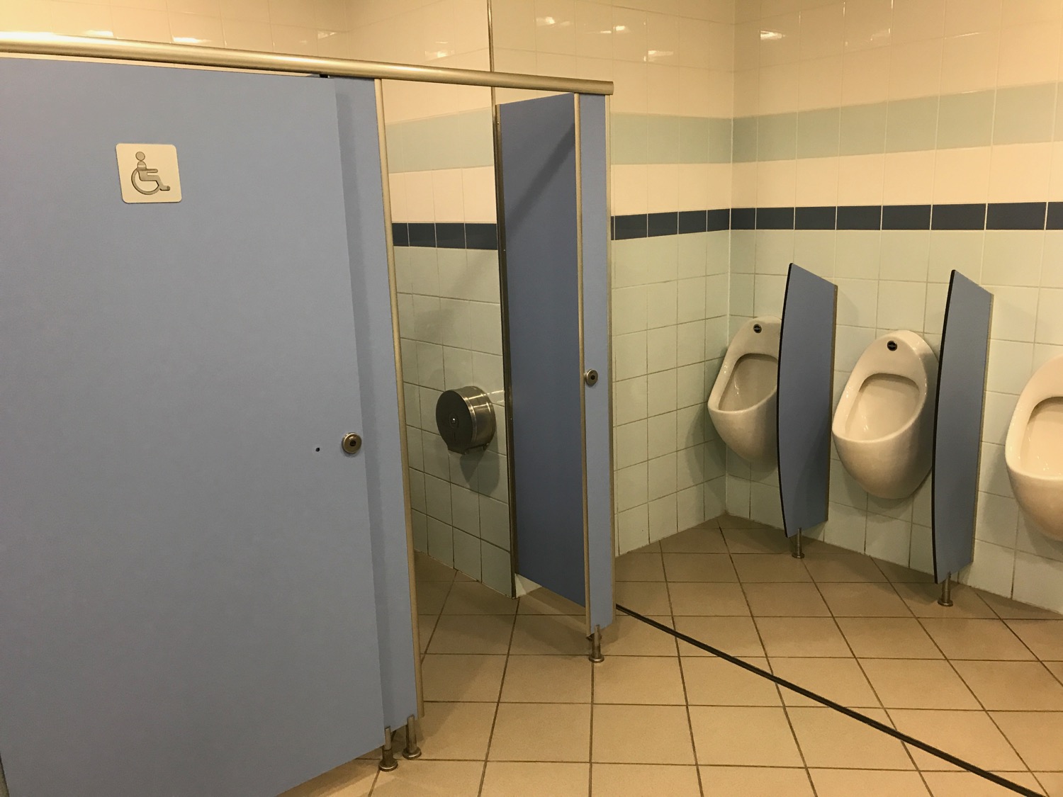 a bathroom with urinals and a blue door
