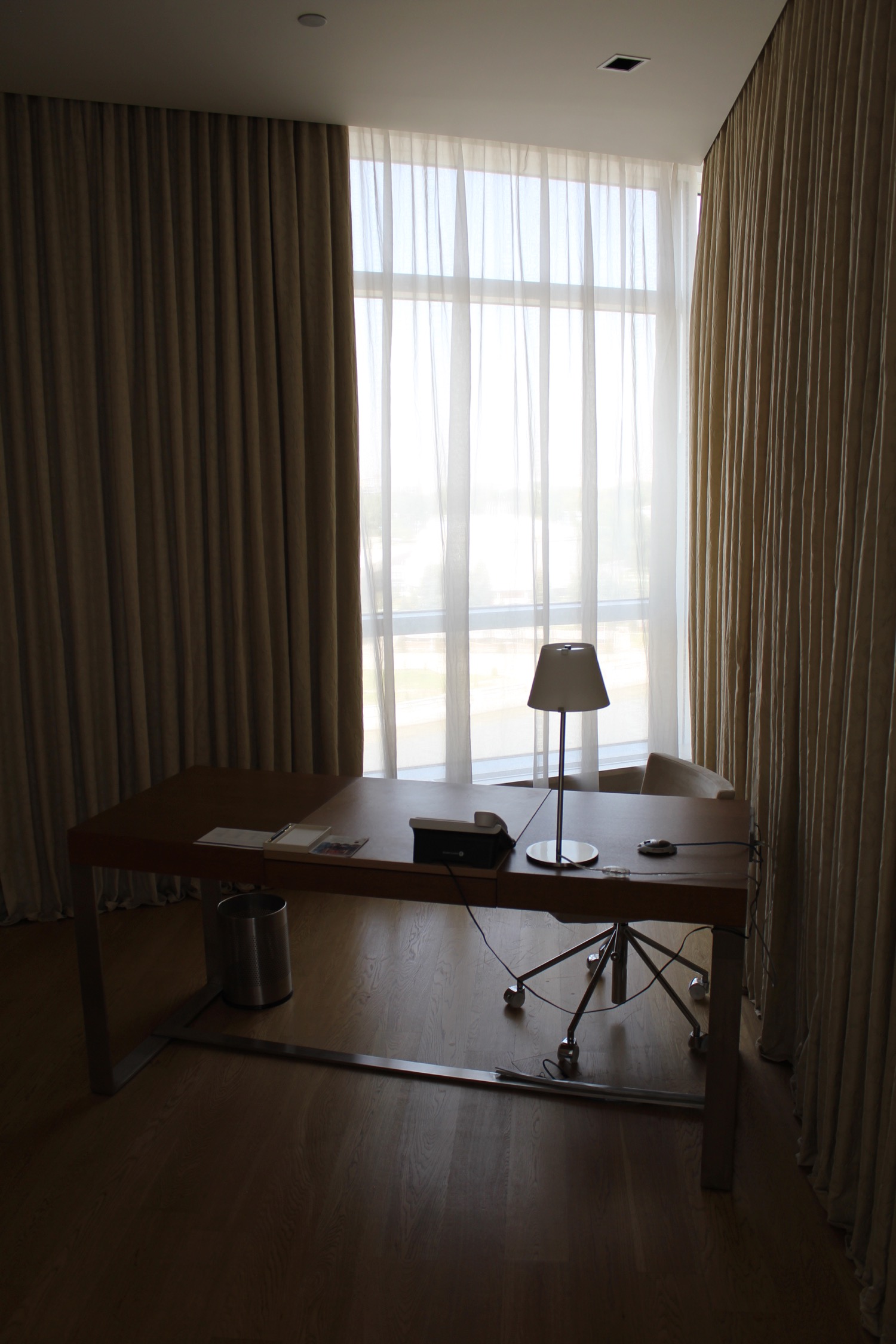 a desk with a lamp and a chair in front of a window