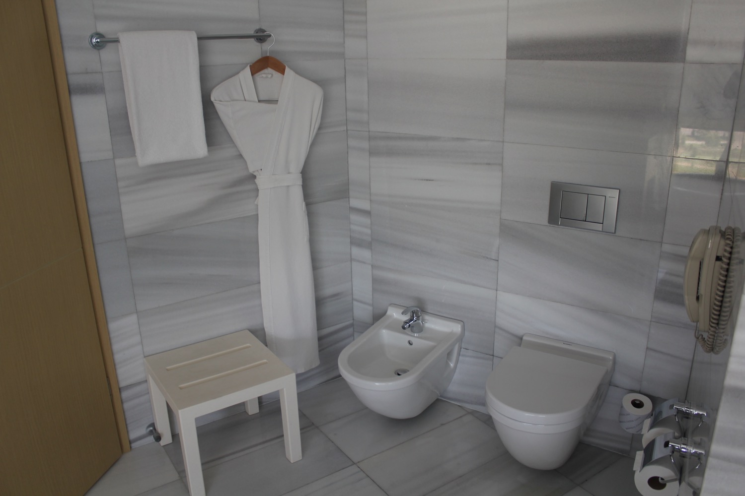 a bathroom with a white robe and a bidet
