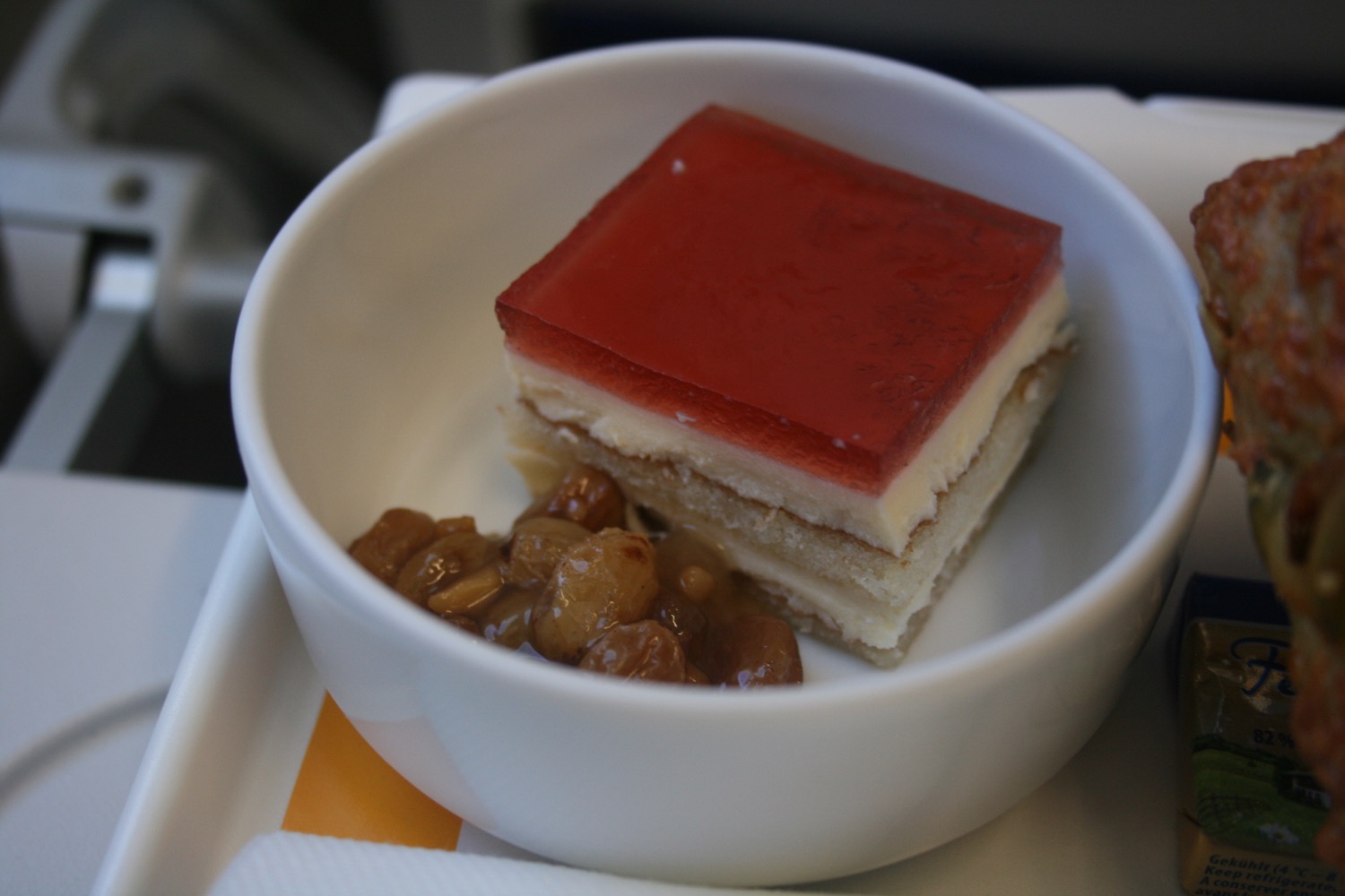 a small white bowl with a piece of cake and raisins