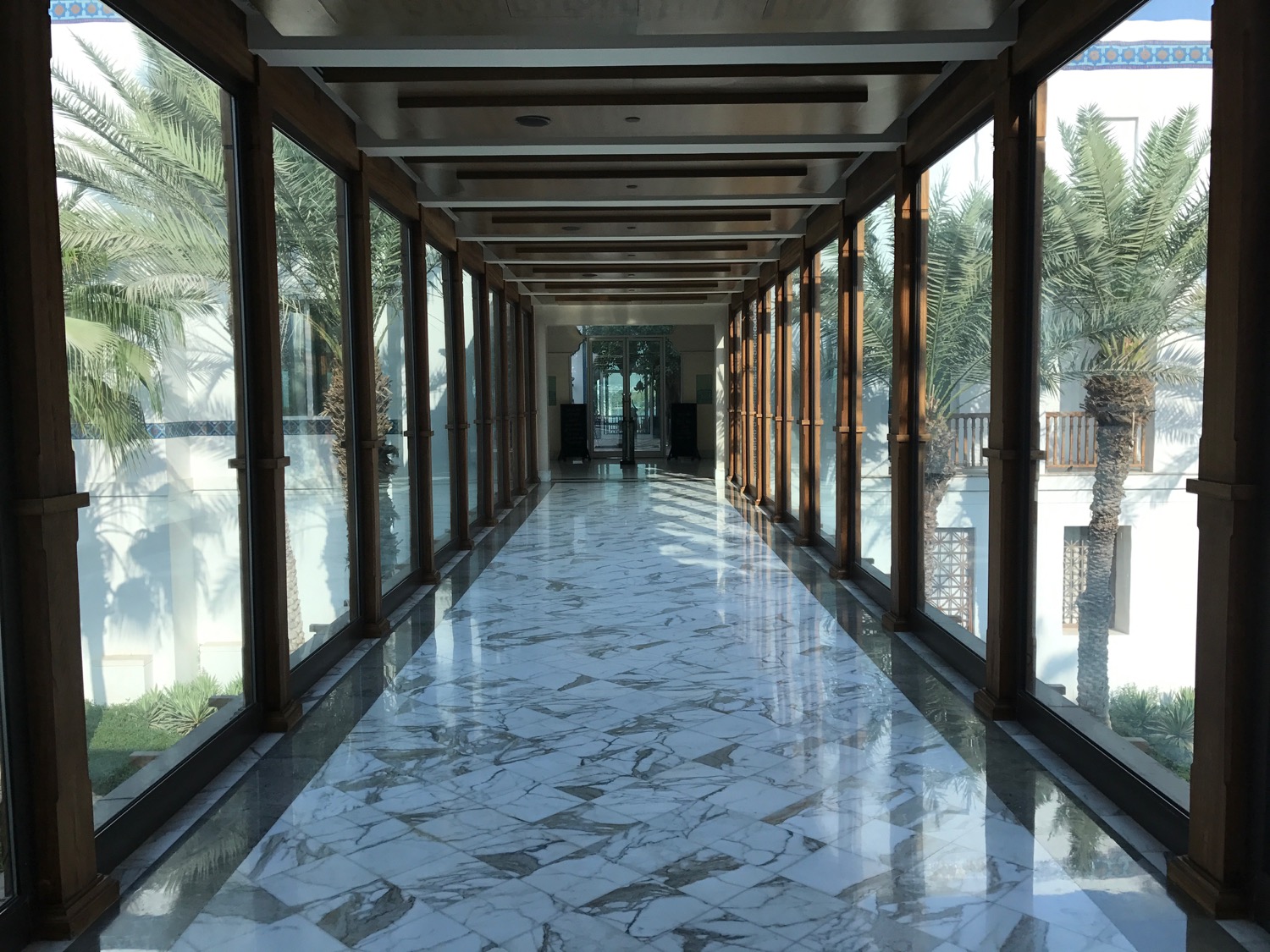 a hallway with glass walls and a marble floor