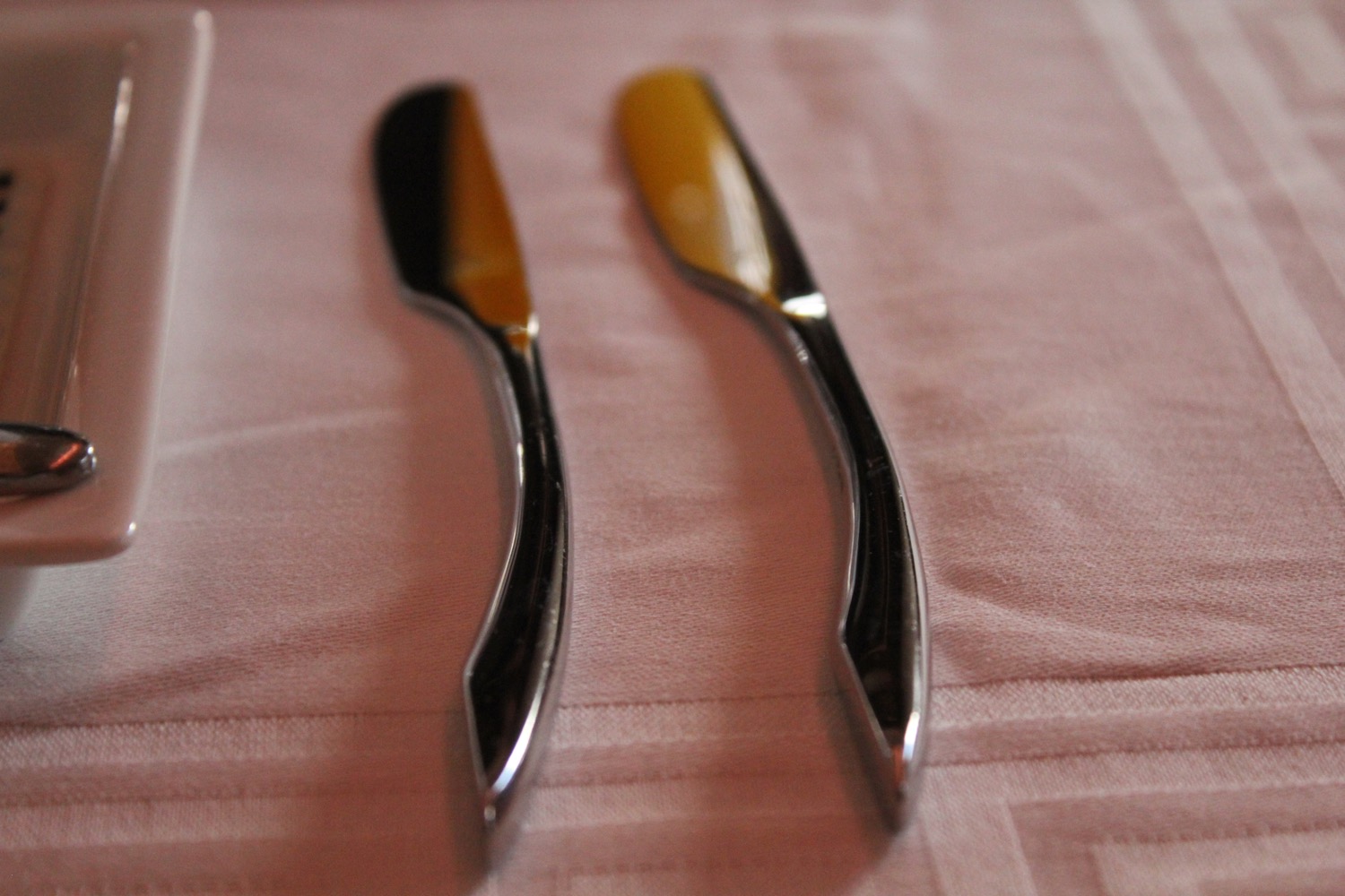 a pair of butter knives on a pink cloth