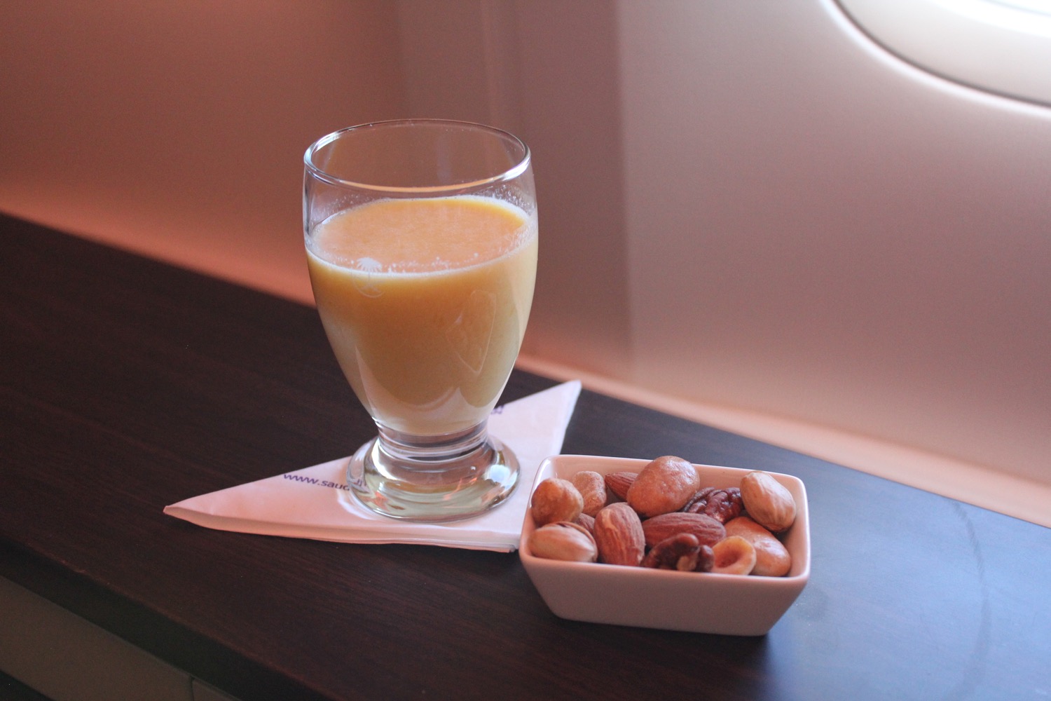 a glass of orange juice and a bowl of nuts