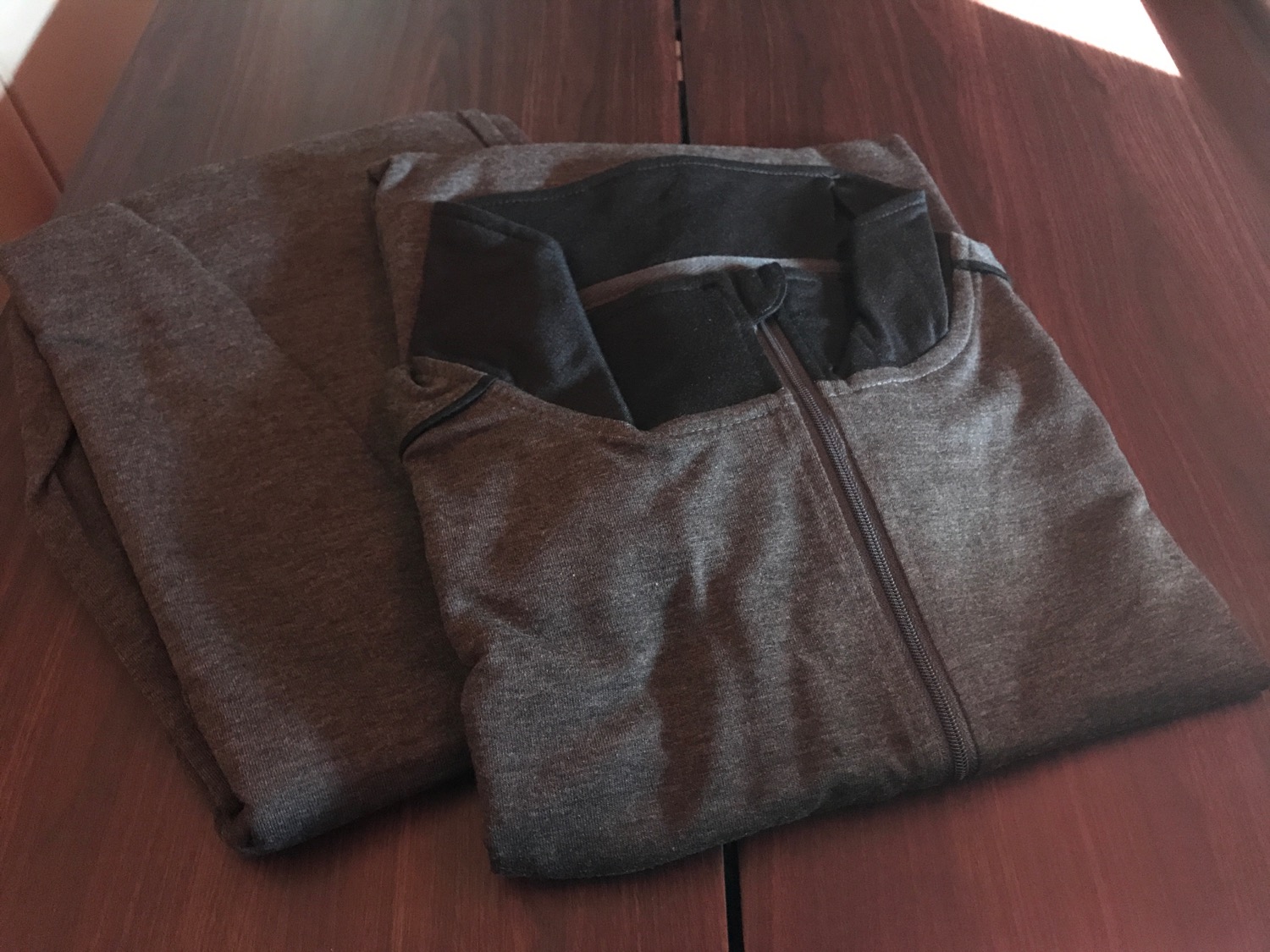 a folded grey sweatshirts on a wooden surface