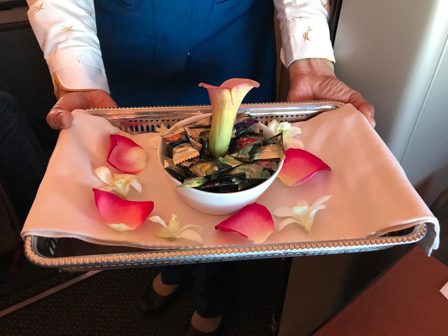 a person holding a tray with a bowl of food and flowers