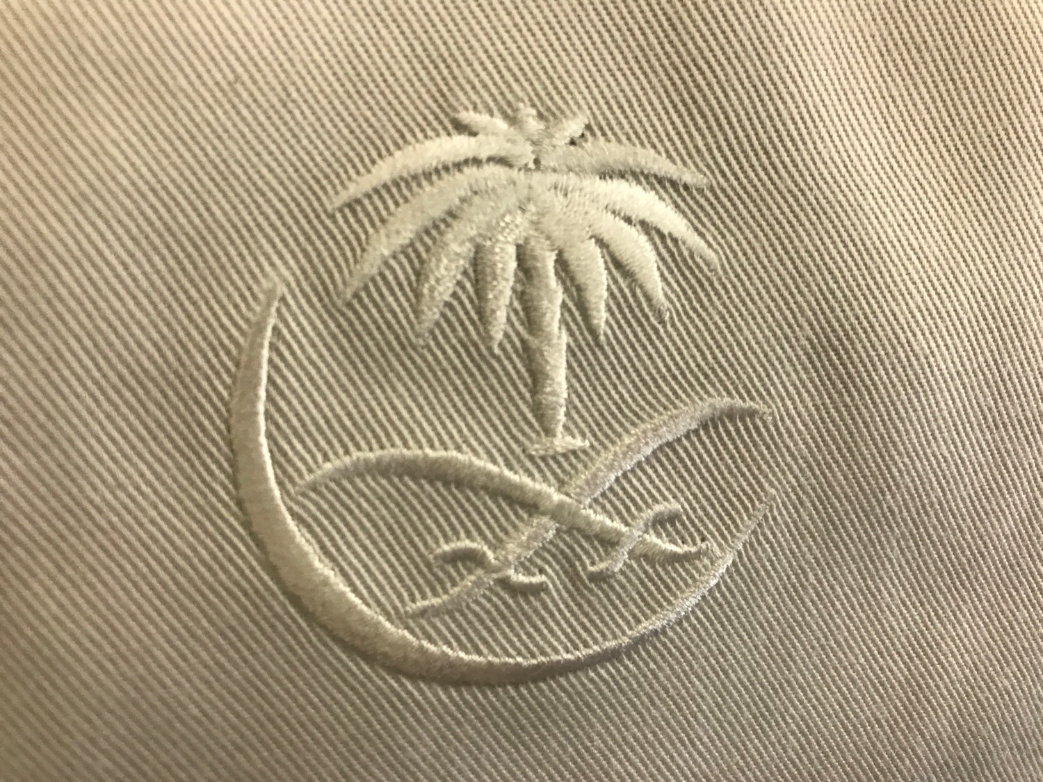 a white embroidered logo on a tan fabric