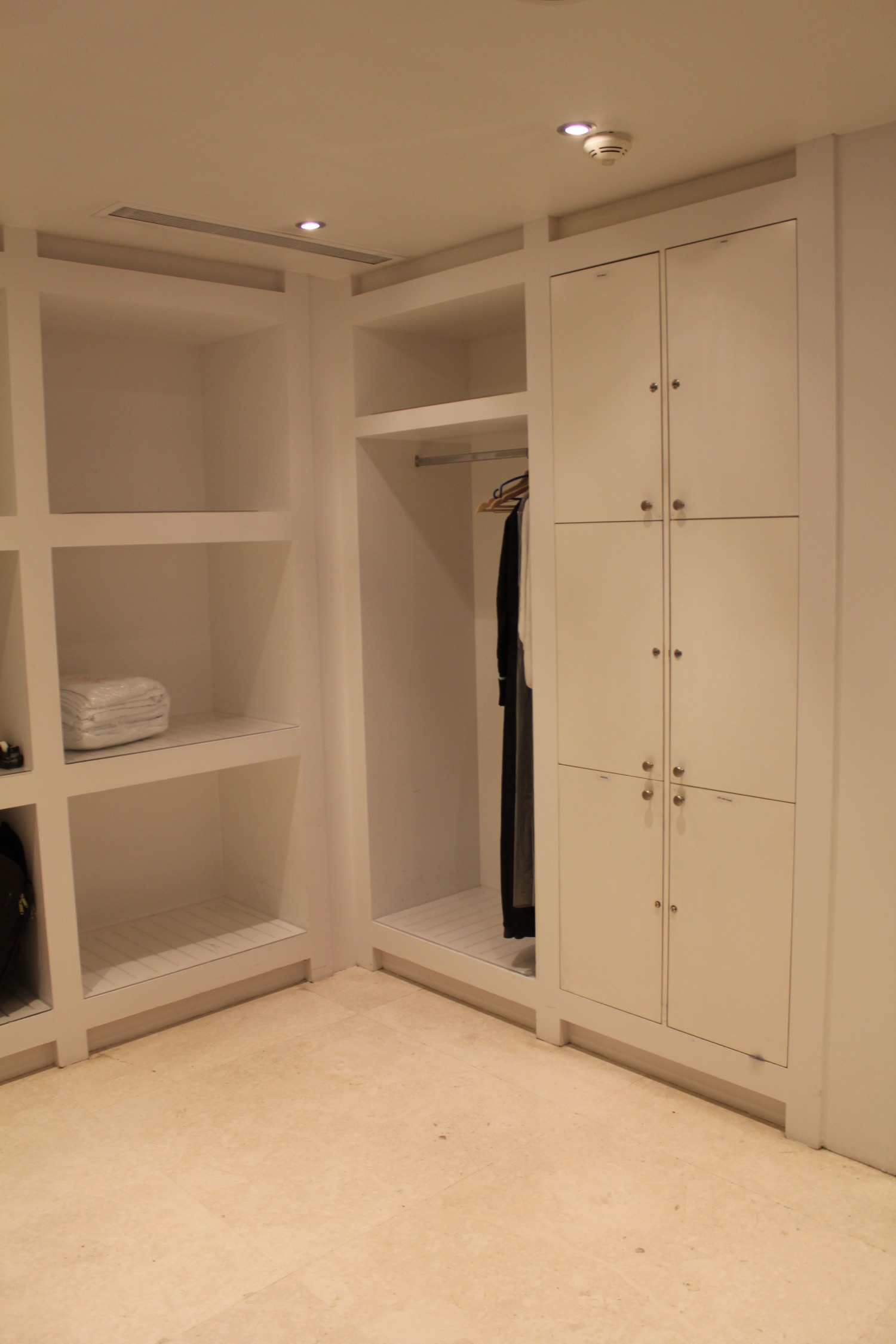 a white closet with shelves and a light on the ceiling