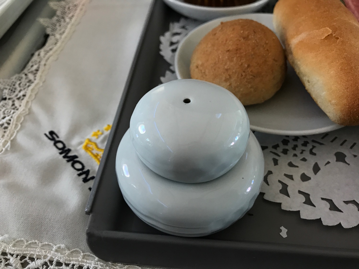 a white salt shaker and a plate of bread