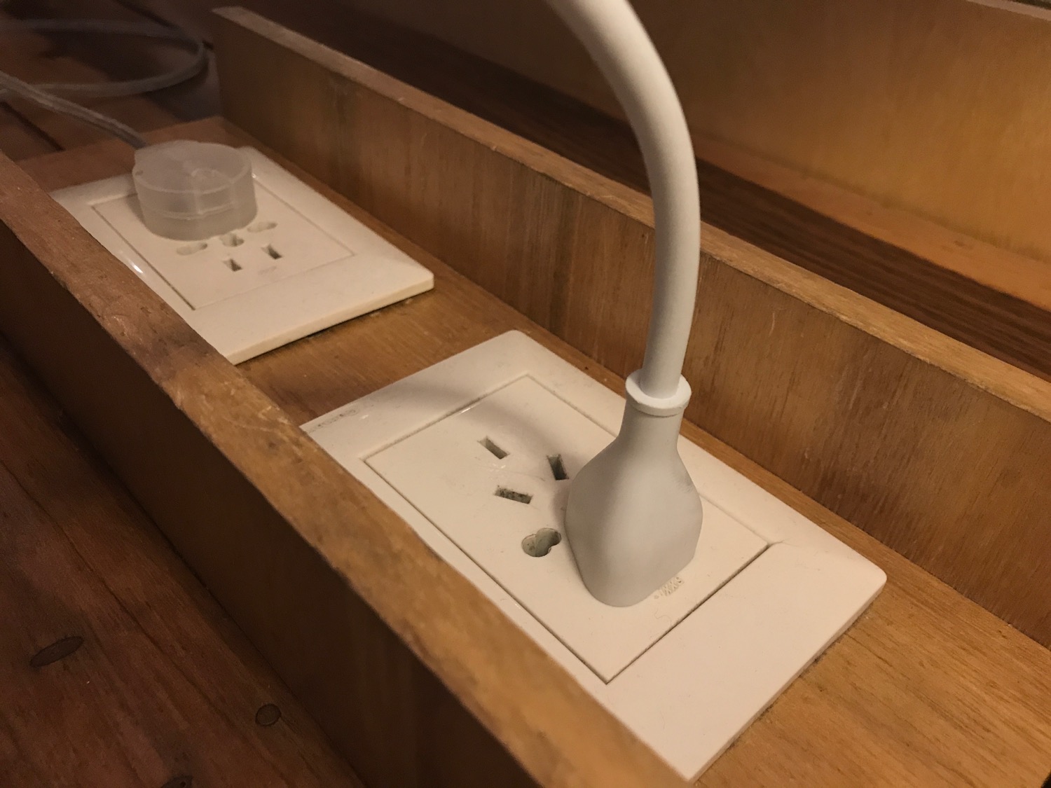 a white electrical outlet with a white cord plugged into it