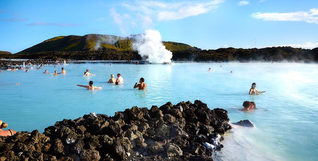 a group of people in a blue body of water with Blue Lagoon in the background