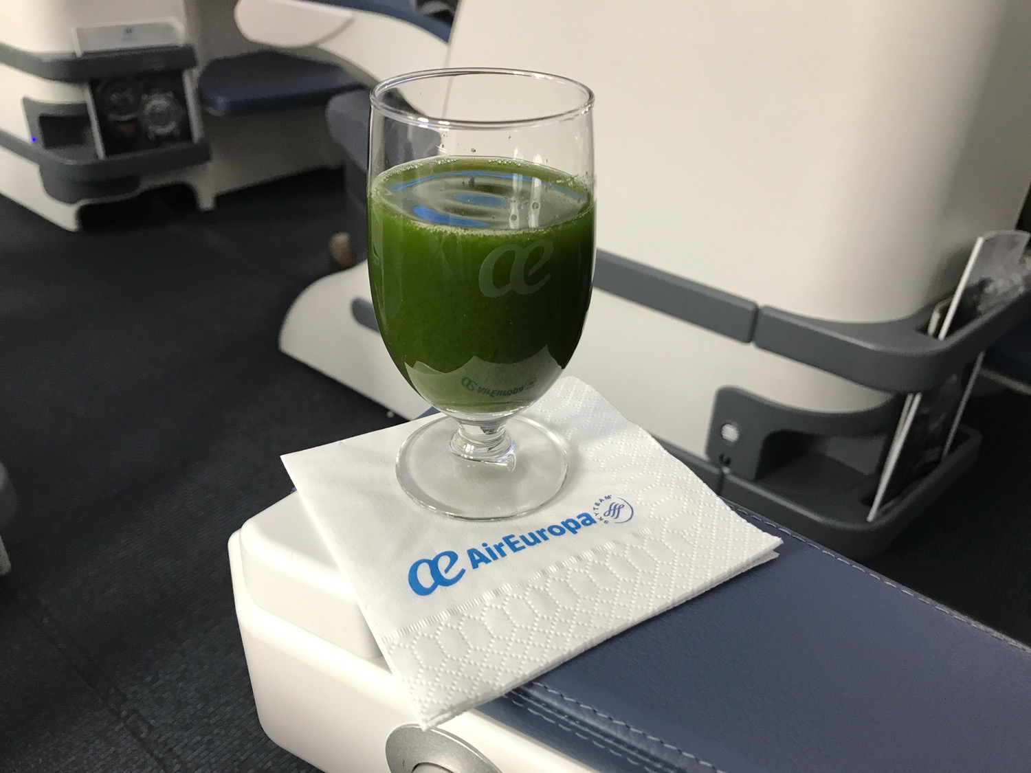 a glass of green juice on a napkin on a table