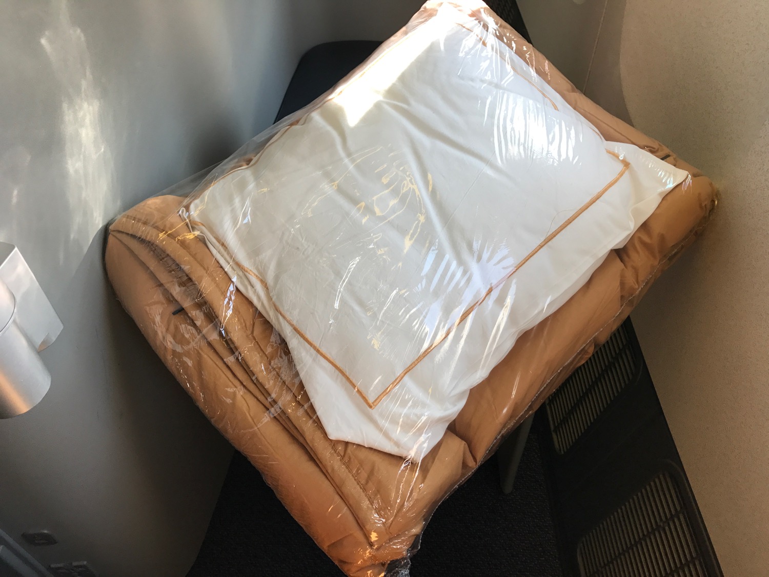 a white pillow and blanket wrapped in plastic