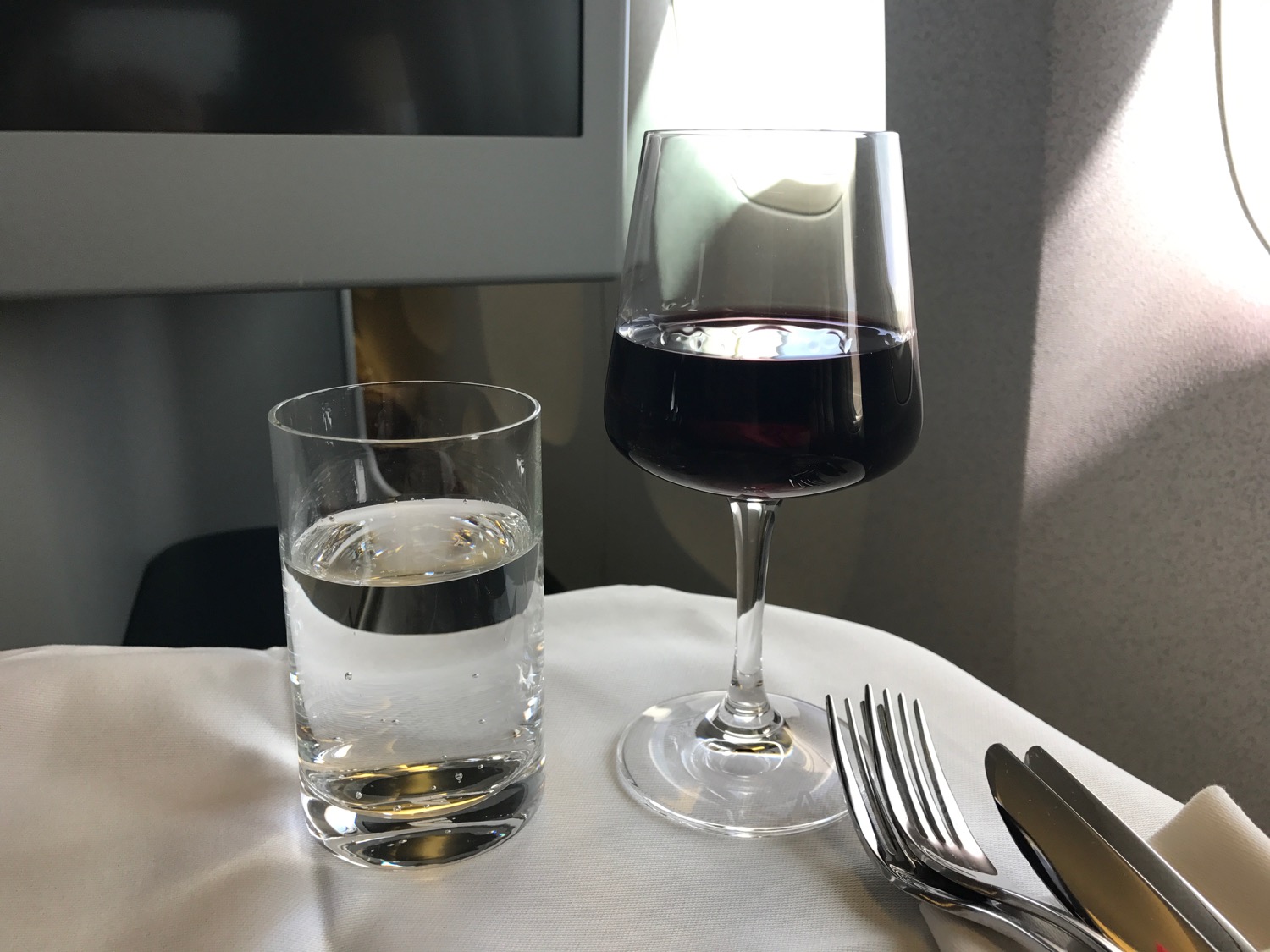 a glass of wine next to a glass of water and silverware