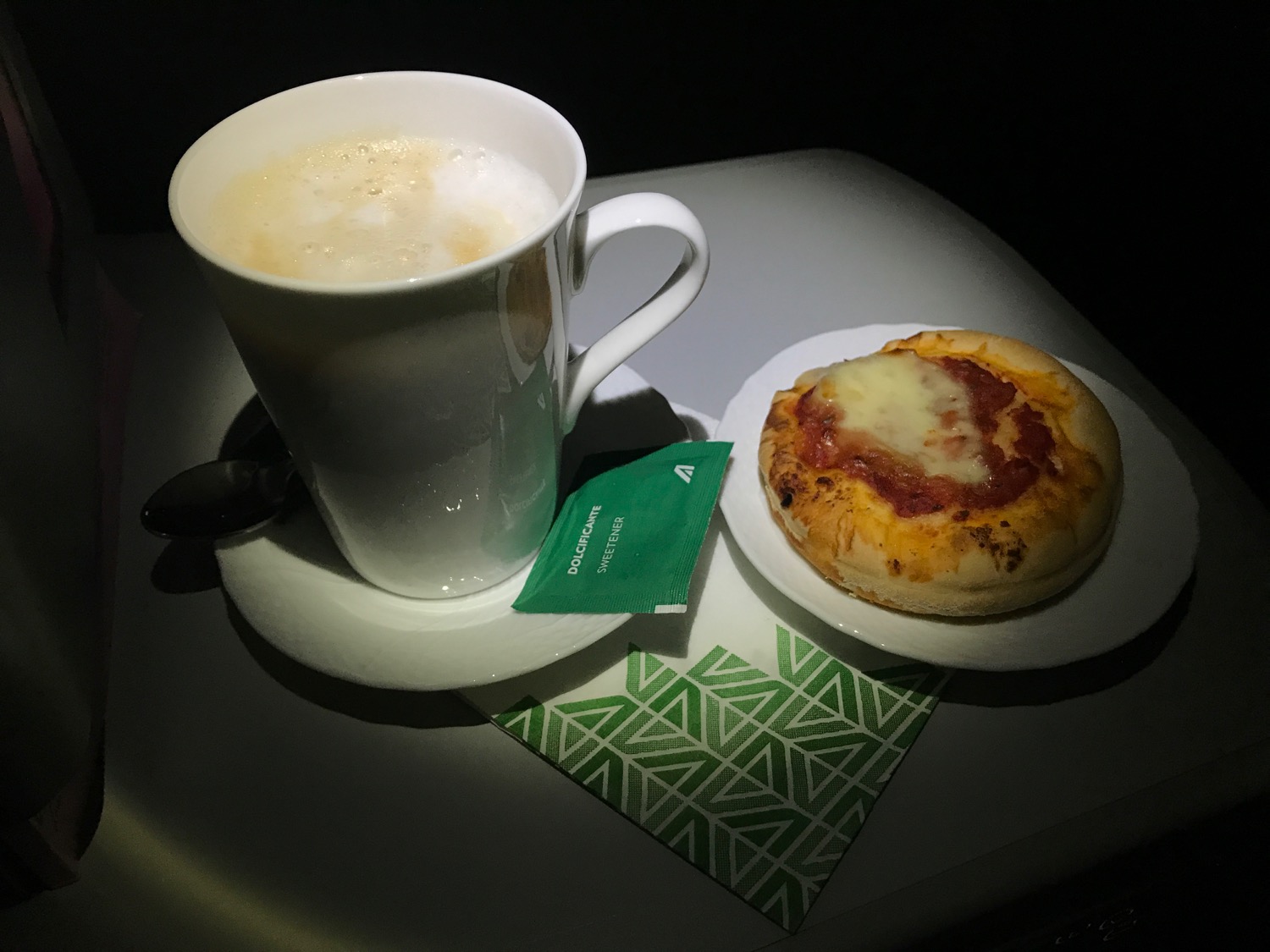 a cup of coffee and a small pizza on a plate