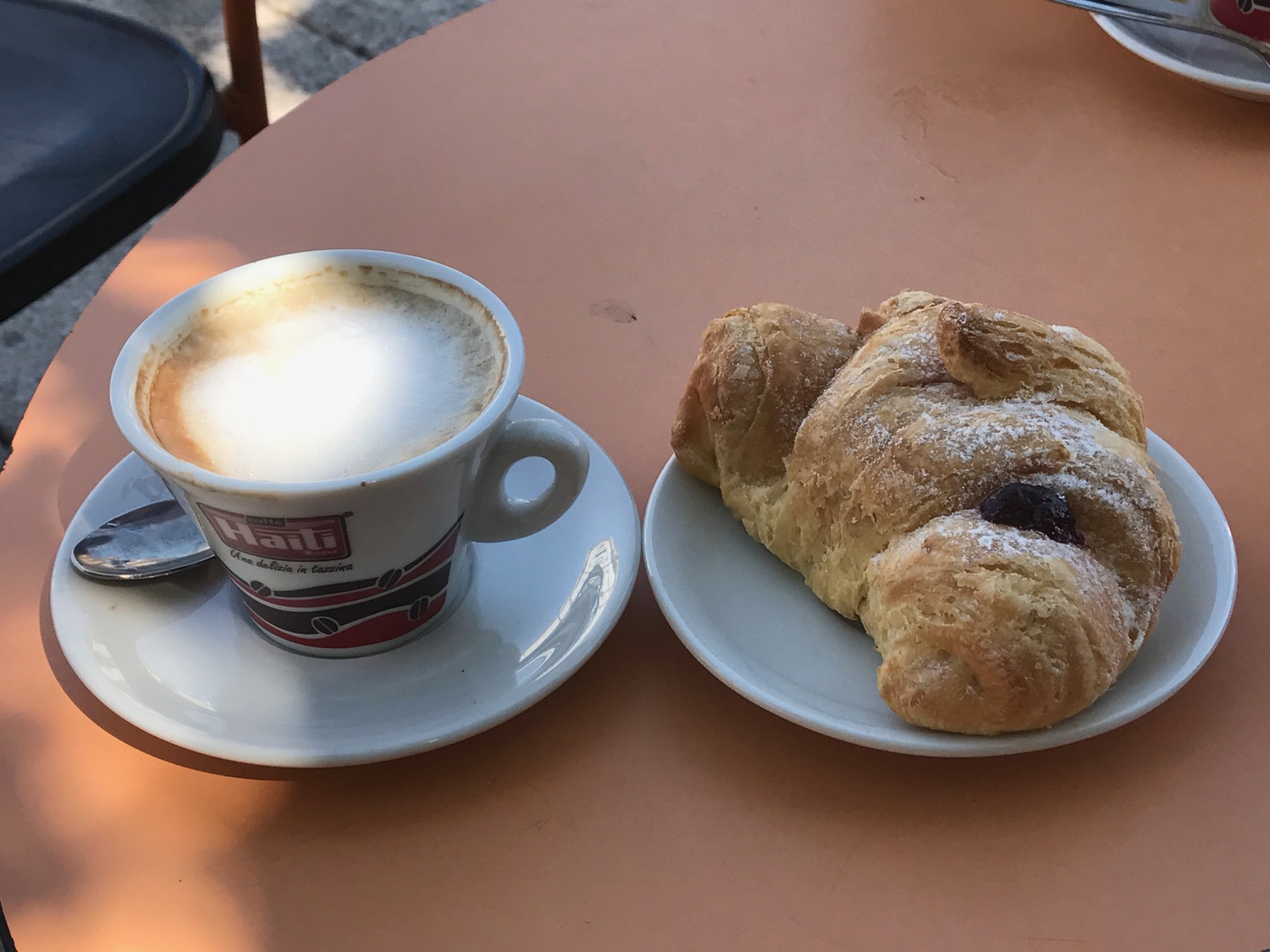 a croissant and a cup of coffee on a table