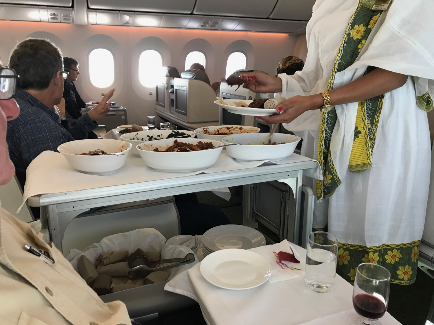 a person serving food on a table in an airplane