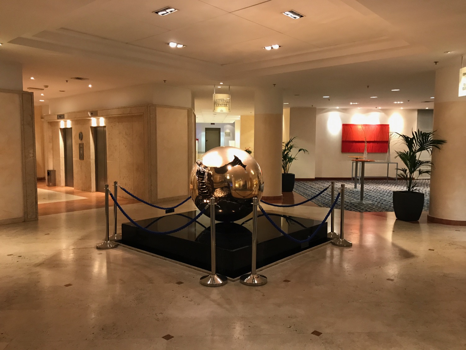 a large round gold object on a black pedestal in a lobby