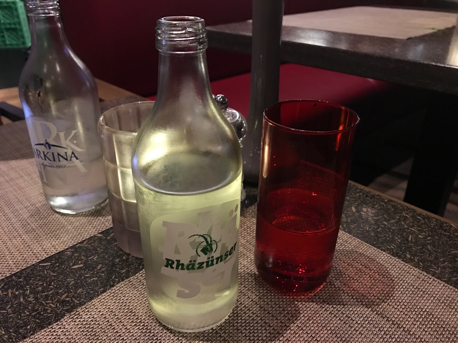 a glass bottle and a red glass on a table