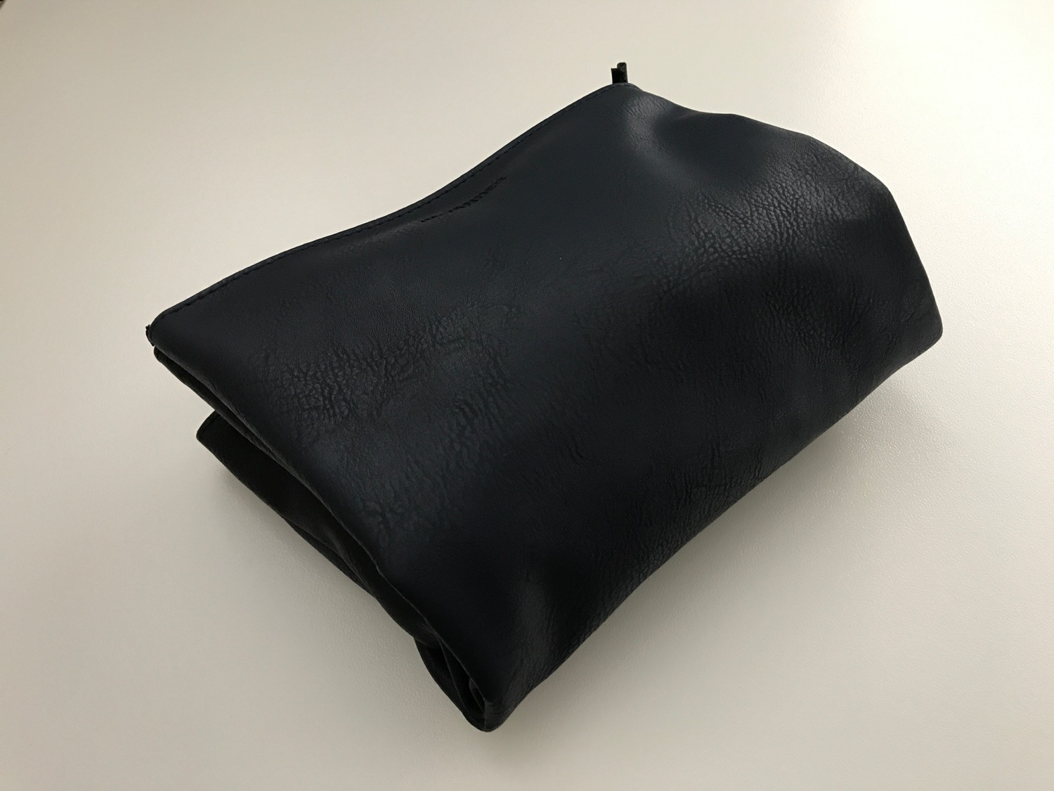 a black leather bag on a white surface