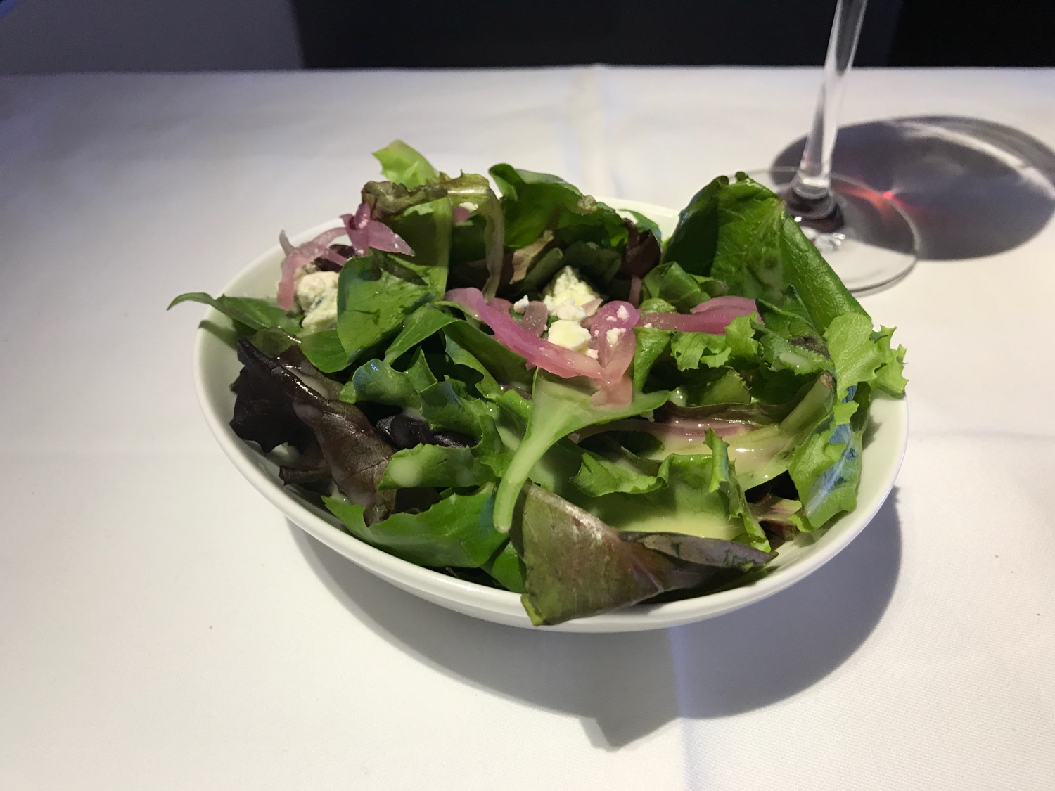 a bowl of salad with a glass of wine